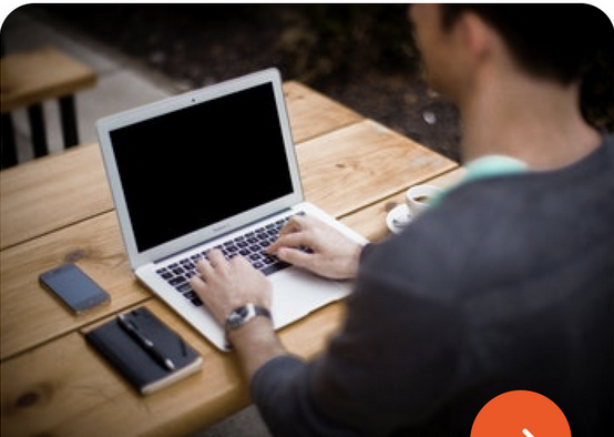 A man typing on a laptop with a dark screen.